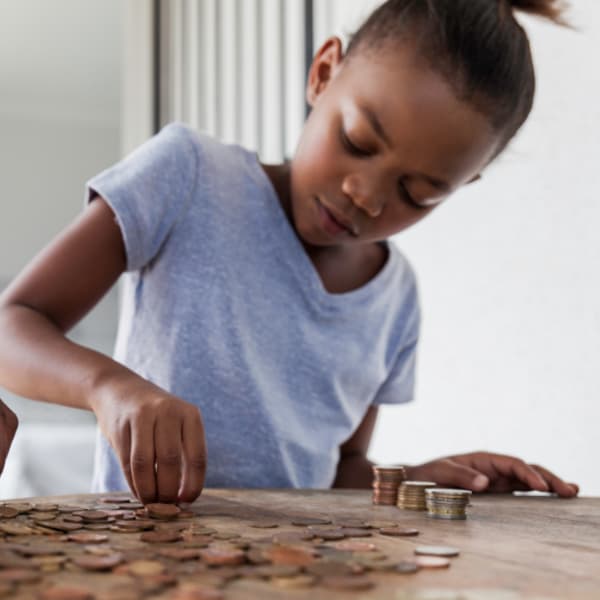 Image of a child counting coins at a table.
