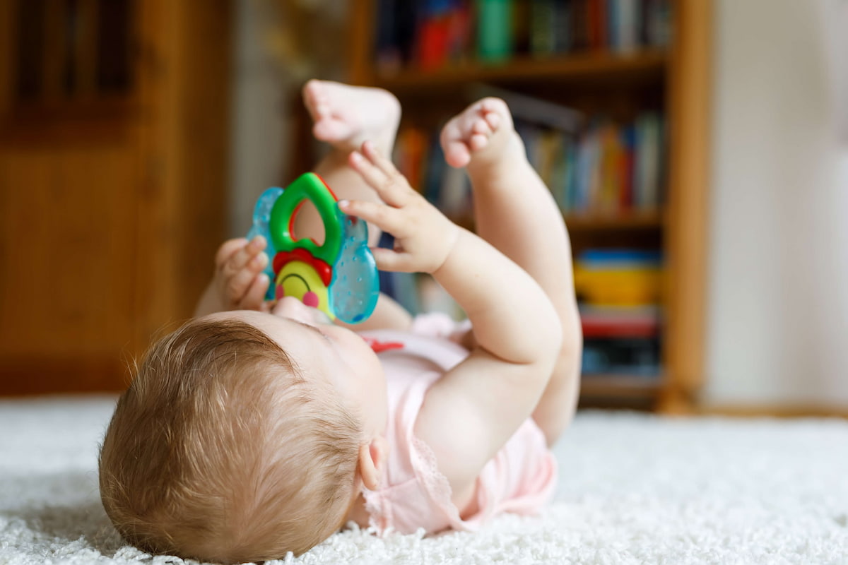 Photo of a baby lying on their back on the ground 
