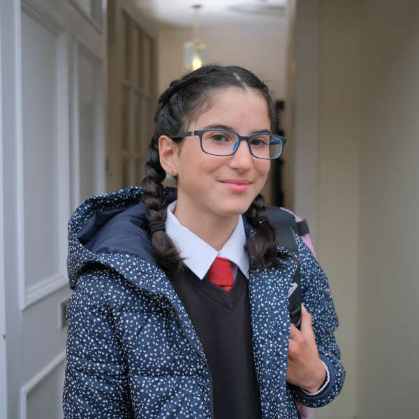 Photo of a girl standing in her school uniform in the doorway 