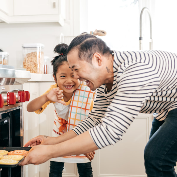 Dad and daughter putting biscuits into the oven