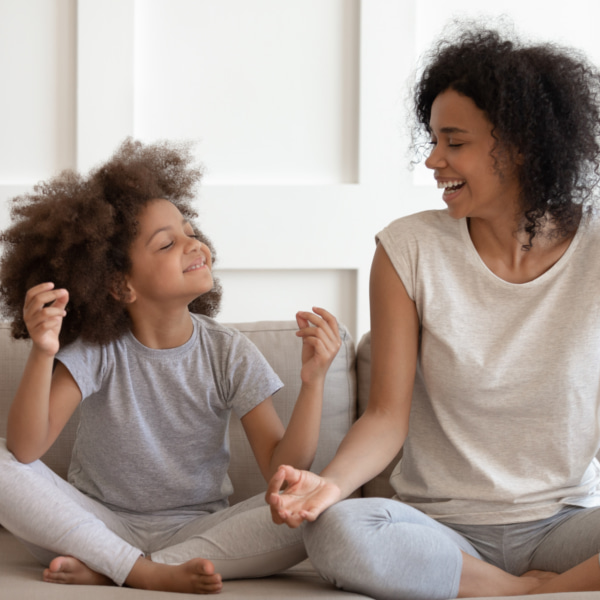 photo of a mum and a child cross legged on the couch laughing 