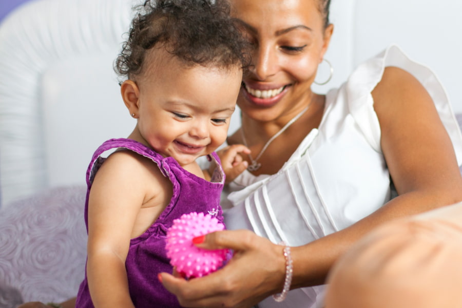 Image of a mum and toddler playing with a ball and laughing together.