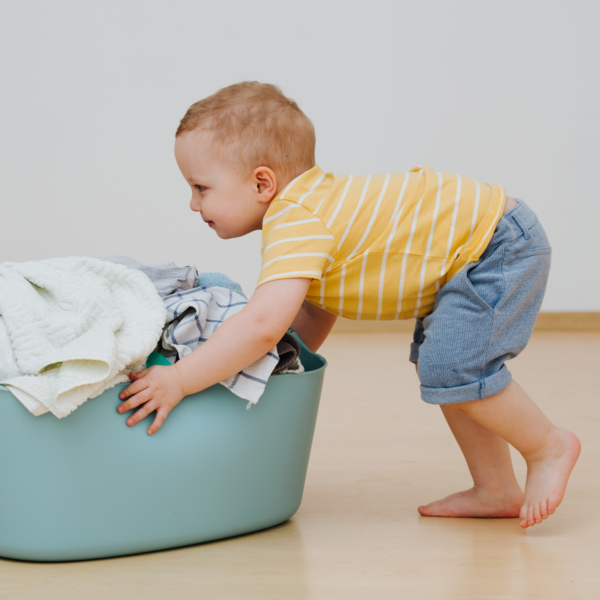 Photo of a toddler pushing a laundry basket