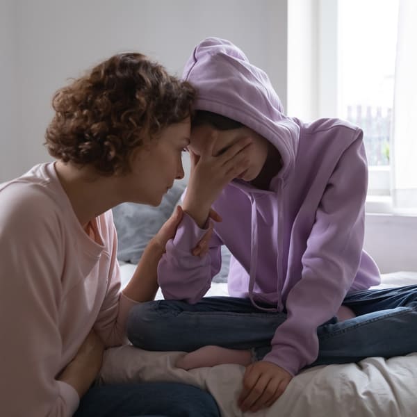 A worried mother comforting her sad teenage daughter