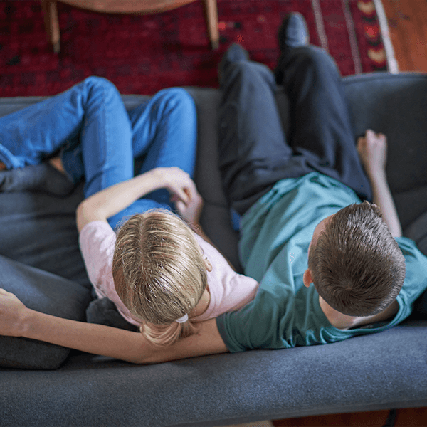 teen-girl-and-boy-sitting-on-couch-together-button