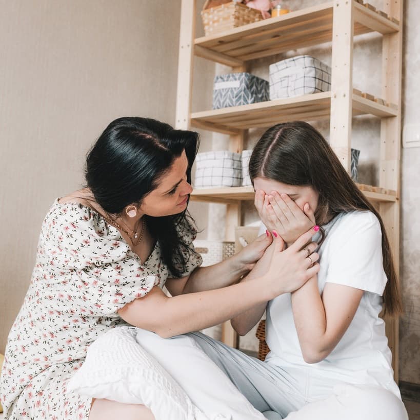 Mother comforting daughter, who looks upset