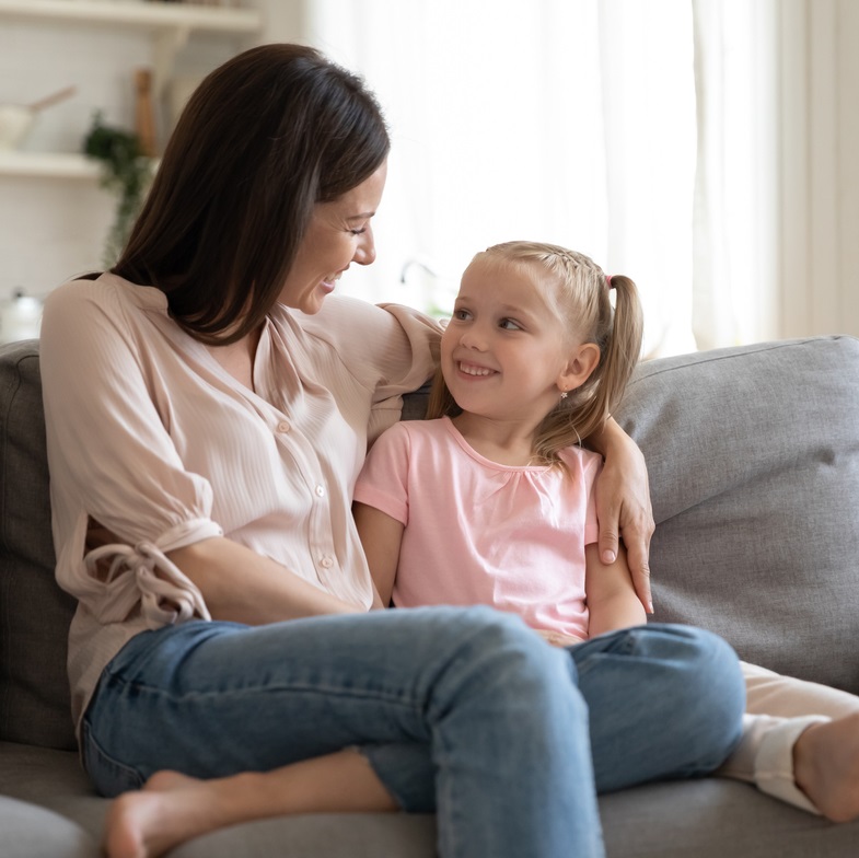 Mother and young girl sitting on the sofa talking
