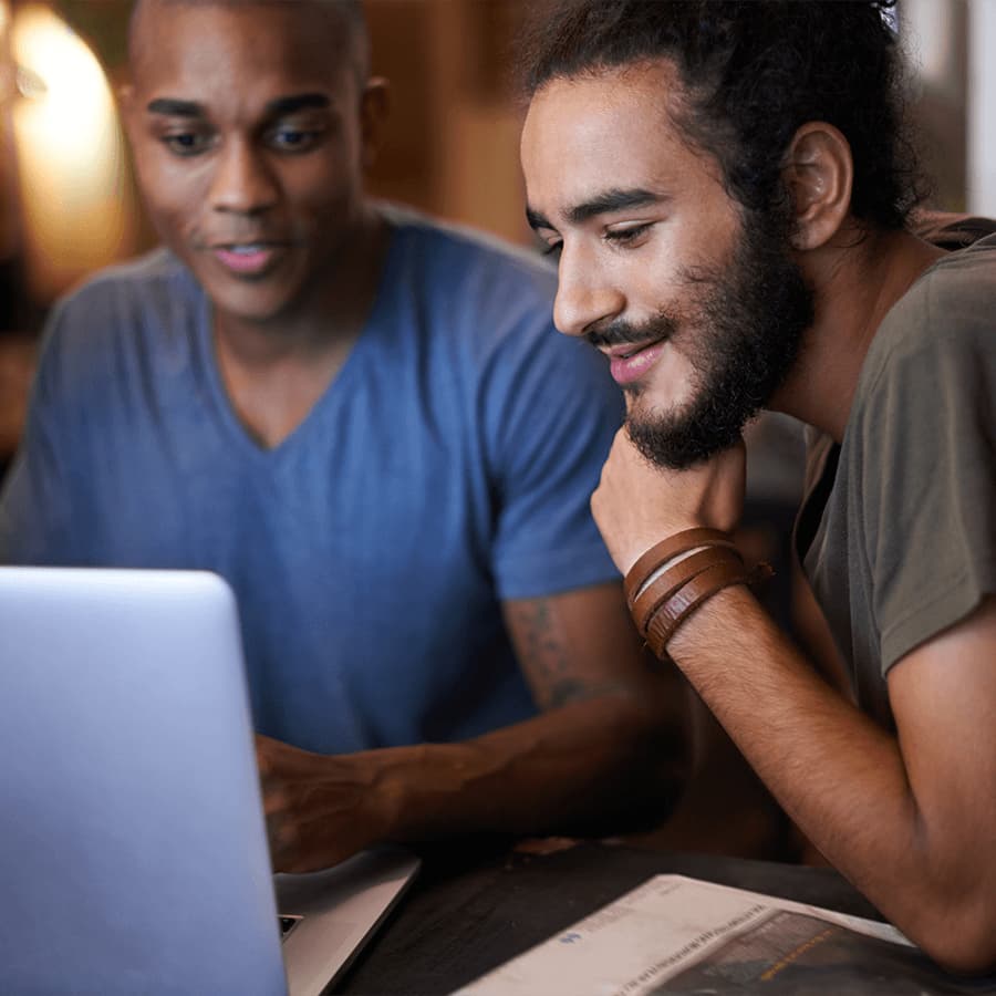 Two men looking at a laptop together, with papers beside them