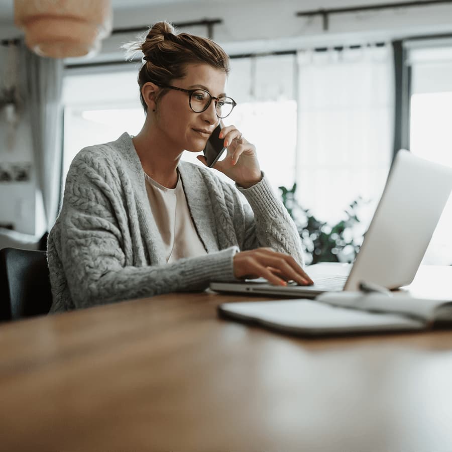 Woman on the phone, looking at a laptop