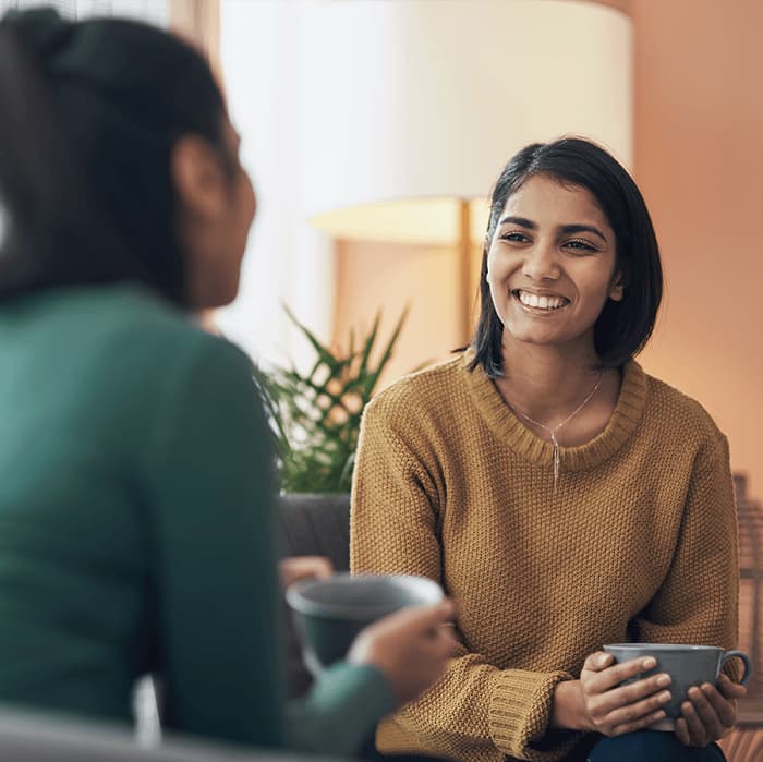 Women talking indoors holding cups