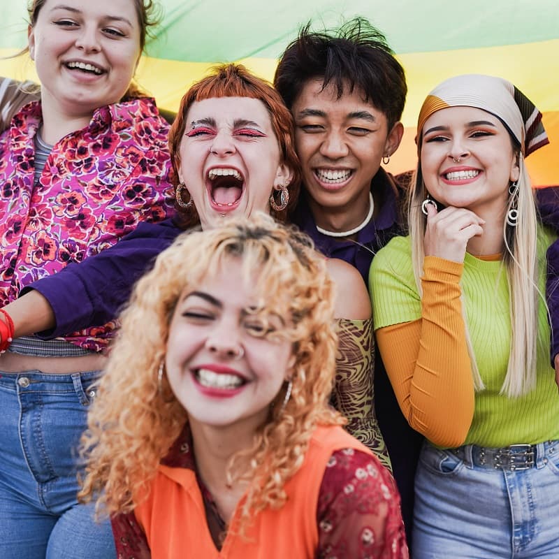Teens wearing brightly coloured clothes, smiling